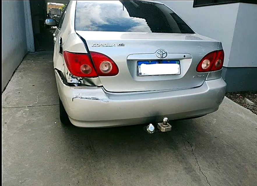 Toyota Corolla prata com o canto traseiro esquerdo amassado e o parachoque raspado antes do reparo